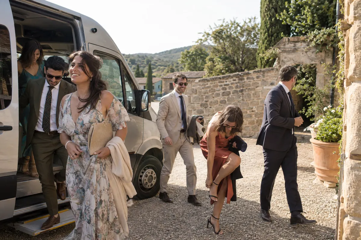 Des invités descendent d’une navette devant l’entrée en pierre du domaine